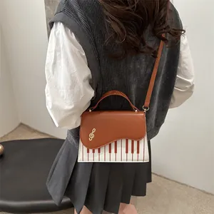 Elegant piano key crossbody bag featuring musical G-clef charm and leather shoulder strap