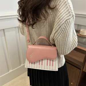 Pink and white piano key crossbody bag with musical note embroidery on shoulder strap