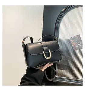 Detail of black leather crossbody bag featuring adjustable strap and golden horseshoe buckle