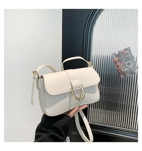 Close-up of a cream white minimalist handbag with a signature gold buckle and leather texture