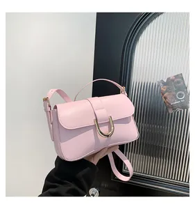 Detail of pink faux leather handbag featuring a gold U-shaped buckle and adjustable strap