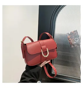 Close-up of red leather square bag featuring elegant gold U-shaped hardware and fine texture
