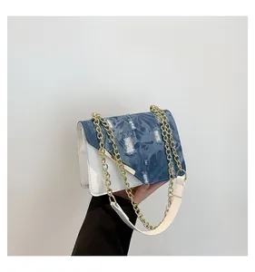 Detail of blue denim and white leather patchwork handbag with gold chain strap