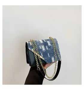 Close-up of distressed blue denim patchwork with golden chain and black leather strap