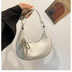 Detail of white hobo bag with textured leather, silver bow bead charm and Fashion logo