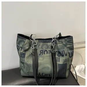 Dettaglio della borsa tote con stampa giornale verde oliva e tracolla a catena su pelle