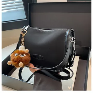 Dettaglio borsa a mezzaluna in nylon nero con fibbia argento e charm in peluche