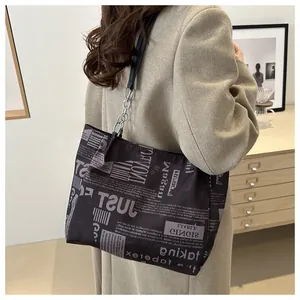 Dettaglio della borsa tote con stampa di giornale, pelle nera e tracolla a catena
