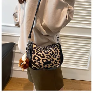 Borsa a tracolla a mezzaluna con stampa leopardata e ciondolo di peluche indossata