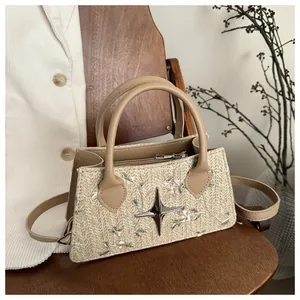 Detail of beige woven handbag with floral embroidery and silver star charm detail