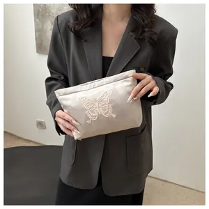 Close-up of elegant butterfly embroidery on satin zipper pouch with detailed stitching