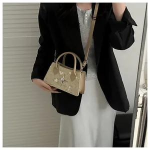 Detail of floral embroidery on a straw shoulder bag worn with a black blazer