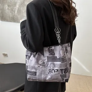 Borsa tote di tendenza in tela con stampa di giornale, manici in pelle nera e catena