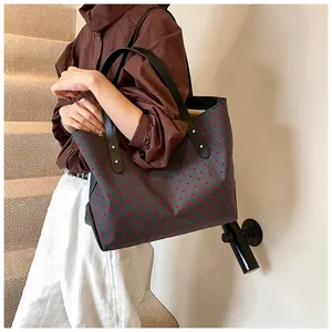 Detail of grey tote bag with red heart patterns and black leather handle on stairs
