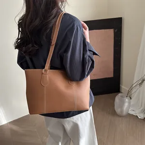 Brown leather tote bag with white contrast stitching for casual everyday shoulder carry
