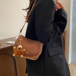 Borsa a spalla a mezzaluna marrone in pelle con ciondolo mostro indossata da modella