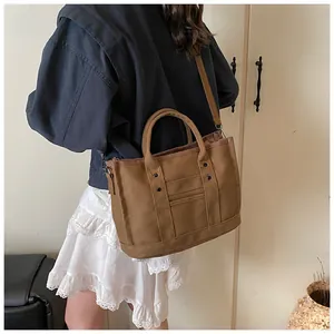 Brown canvas tote bag detail showing metal rivets and textured material with shoulder strap