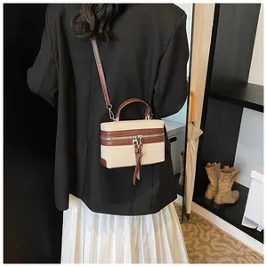 Détail du sac à main en toile bicolore avec bordures en cuir marron et finitions