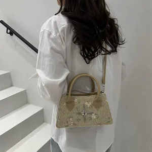 Straw handbag with pink floral embroidery and metal star accent on a beige woven body