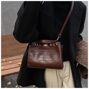 Gros plan d'un sac à main marron à motif crocodile avec fermoir en métal doré