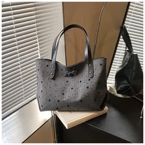 Detailed view of dark grey tote bag with black star pattern and silver bow charm