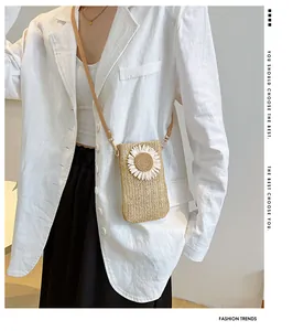 Detail of straw woven crossbody bag with daisy flower worn by model in white suit