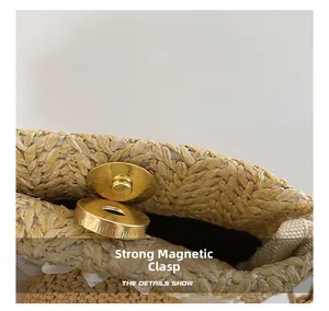 Detail view of the strong gold magnetic buckle closure on a woven straw handbag