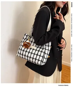 Detail of checkered tweed tote bag featuring cream leather strap and plush charm