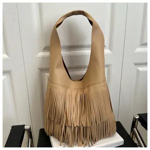 Macro detail of camel brown hobo bag showing litchi grain leather and long fringe tassels