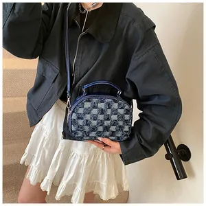 Detailansicht der dunkelblauen Denim-Umschlagtasche mit Karomuster und Fransen
