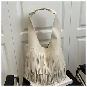 Detail of white litchi leather hobo bag with long fringe tassels on white book