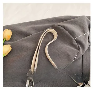 Detail shot of the cream leather shoulder strap with durable stitching and silver metal ring