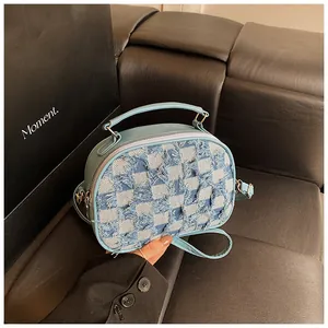 Detail der hellblauen Denim-Umschlagtasche mit Karomuster, Fransen und Kurzgriff