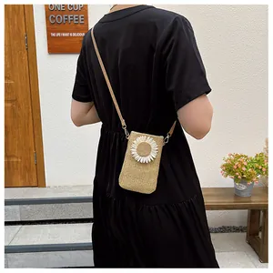 Close-up of straw crossbody bag with white daisy flower detail on a black dress