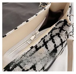 Detail of smooth metal zipper and internal pocket on a black and white plaid tweed tote bag