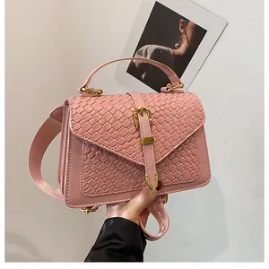Pink woven crossbody bag with gold metallic buckle and adjustable shoulder strap detail