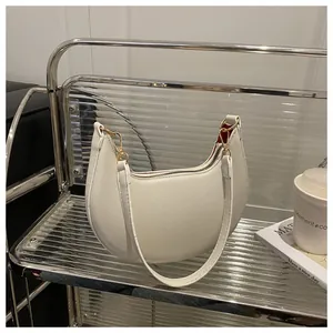 Detailed shot of white crescent shoulder bag with lychee leather and gold hardware
