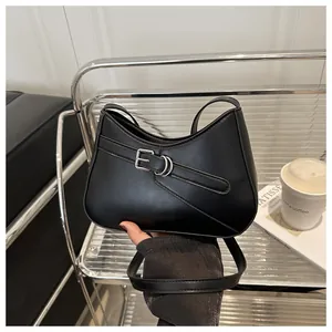 Detalle del bolso de hombro negro con textura de cuero mate y hebillas plateadas