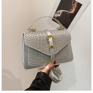 Detail of silver gray square bag featuring woven texture and golden metal buckle