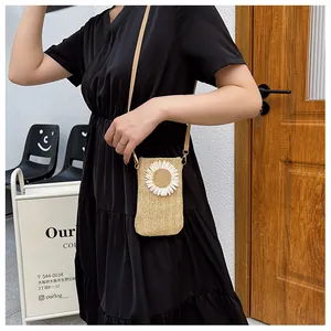 Straw woven crossbody phone bag with sunflower detail worn over a black dress