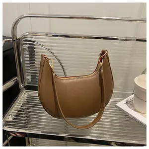 Detail view of brown pebbled leather crescent bag with gold zipper and stylish metal buckle