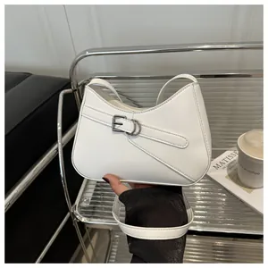 Detalle de bolso de hombro en cuero blanco con hebilla plateada en estante moderno