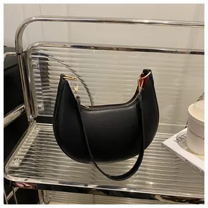 Detailed close-up of black lychee grain leather crescent bag with golden metal zipper