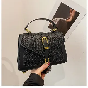 Close-up of black woven leather handbag showing honeycomb texture and gold metal buckle