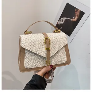 Close-up of woven off-white texture with khaki leather trim and gold buckle on a handbag