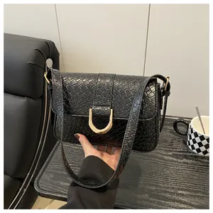 Detailed view of crocodile texture synthetic leather and golden buckle on black handbag