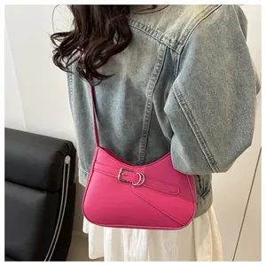 Detalle de bolso de axila en cuero rosa con hebilla plateada y correa fina de hombro