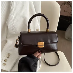 Detail of dark brown vintage handbag featuring glossy leather texture and gold metal buckle