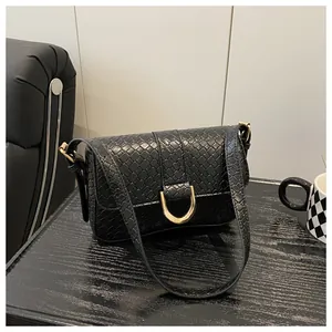 Detail of black crocodile pattern leather texture with a gold metal D-shaped buckle