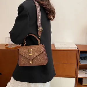 Retro brown woven crossbody bag with wide patterned strap and golden hardware